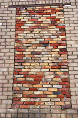 A bricked-up window opening in the brick wall of an old industrial building.