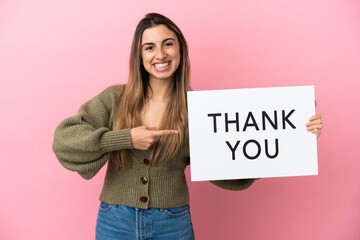 Young caucasian woman isolated on pink background holding a placard with text THANK YOU and ...