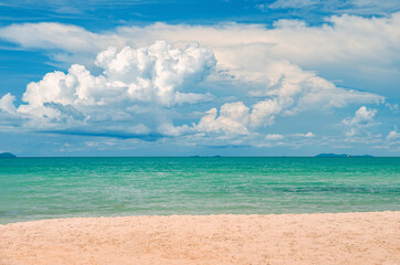 Tropical beach with white sand, turquoise ocean and beautiful clouds in the sky.