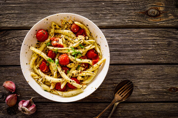 Roasted tomatoes with feta cheese and maccheroni al ferretto served on wooden table
