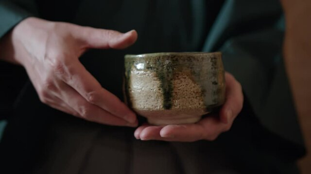 The tea master turning a chawan bowl with the prepared matcha tea  before handing it to a guest. Traditional Japanese tea ceremony chanoyu is a famous Japanese custom, art and Zen Buddhism practice