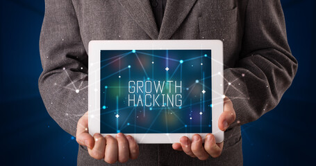 Young business person working on tablet and shows the digital sign: GROWTH HACKING