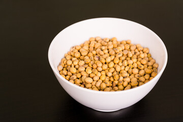Soybean seeds grains in round white bowl on black table