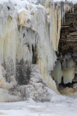 Close up of beautiful frozen Jagala (Estonian - Jägala) waterfall at cloudy winter morning. Cascading icicles. Selective focus.