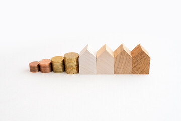 Coins and wooden models of houses represent financial growth, real estate financing and investing in real estate.