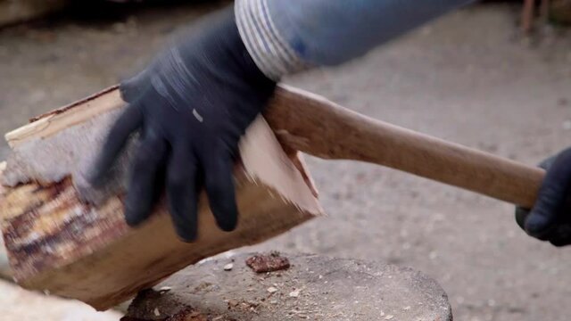 a man chops firewood with an ax in the yard. Close-up.