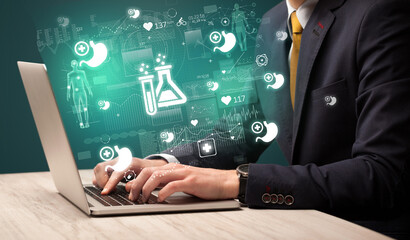 hand browsing on the internet for medical issues with chemical icons coming out from the screen