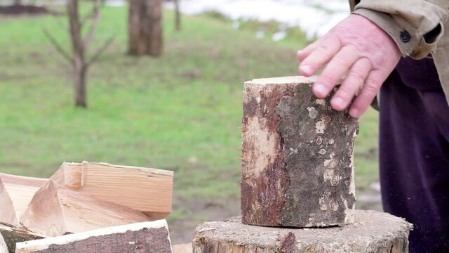 a man chops firewood with an ax in the yard. Close-up slow motion.
