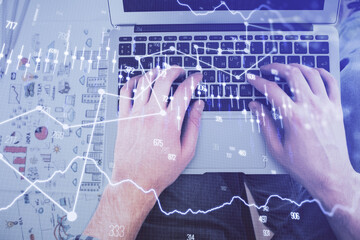 Double exposure of man's hands typing over laptop keyboard and forex chart hologram drawing. Top view. Financial markets concept.