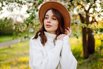 Young woman enjoying scent in blooming spring garden. The concept of youth, love, fashion and lifestyle.