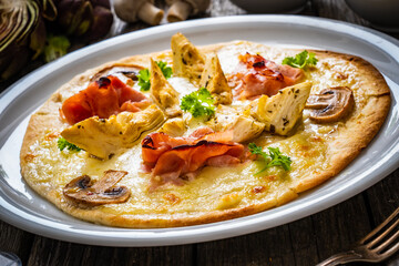 Pizza with artichokes, champignons, ham and mozzarella on wooden background

