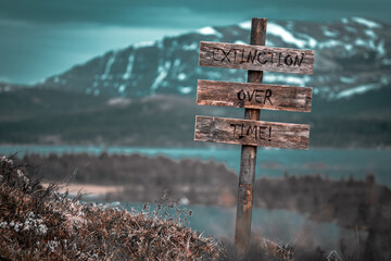 extinction over time text quote engraved on wooden signpost outdoors in landscape looking polluted and apocalyptic.