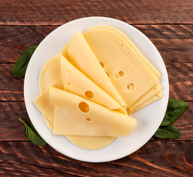 Slicing Cheese In A Plate On A Wooden Background. Top View