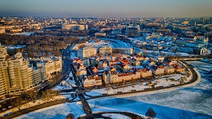 Obraz premium Panoramic cityscape of Minsk downtown at sunset. An old suburbs next to a modern multi-storey house on the shore of a frozen river.