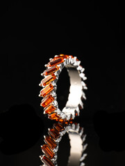 ring jewelry with glass colored stones with reflection on black background