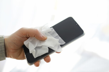 Сleaning concept. Wipe dirt off surfaces. Disinfectant treatment of phone screenl. Sanitary treatment at home quarantine.