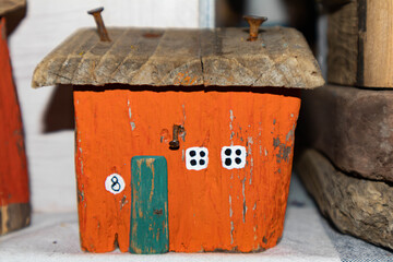 Old wooden orange house. Rusty nails are driven into the roof. Small white windows. Miniature hut.