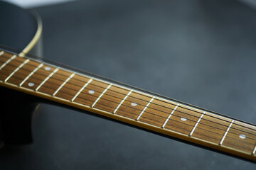 Fototapeta premium An acoustic guitar for an artist playing a stringed musical instrument on stage. Black guitar with a capo. Musical background.