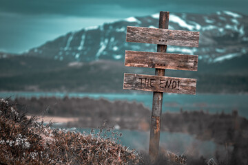 ... ... the end text quote engraved on wooden signpost outdoors in landscape looking polluted and apocalyptic.