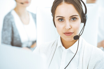 Call center. Group of diverse operators at work. Beautiful woman in headset communicating with customers of telemarketing service. Business concept