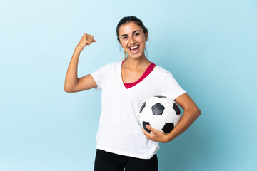 Young hispanic woman over isolated blue background with soccer ball celebrating a victory