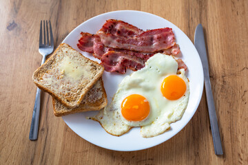 Tasty breakfast with two eggs, bacon, toasts and coffee