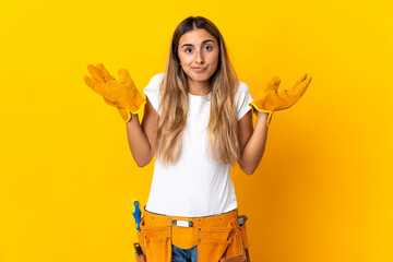 Young hispanic electrician woman over isolated yellow wall having doubts while raising hands