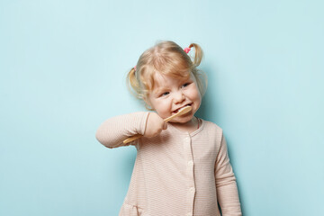 child girl brushing teeth on blue background.