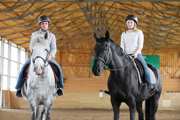 People on a horse training in a wooden arena