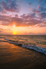 Naklejka premium beautiful golden sunset on the beach over the sea with some dreamy clouds