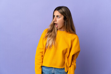Young hispanic woman over isolated purple background doing surprise gesture while looking to the side