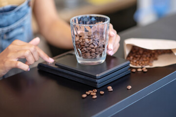 Female hands weighing coffee beans in glass