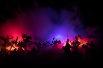 Medieval battle scene with cavalry and infantry. Silhouettes of figures as separate objects, fight between warriors on sunset foggy background.