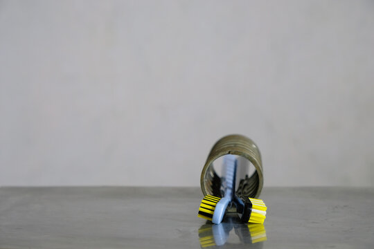 Heads of modern toothbrushes. Hard yellow, black, white bristles. Metal spring, metallic gray background. Copy space.