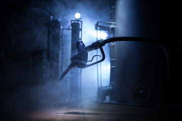 Creative concept. Silhouette of gasoline pistol miniature on dark toned foggy background. Close up. Industrial decorated elements on background.