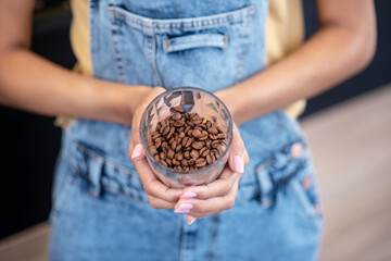 Female hands holding glass of coffee beans
