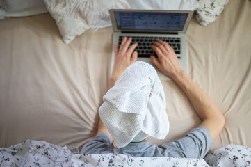 woman with laptop in bed work from home