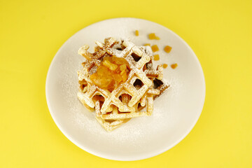 Waffles with jam on a yellow background