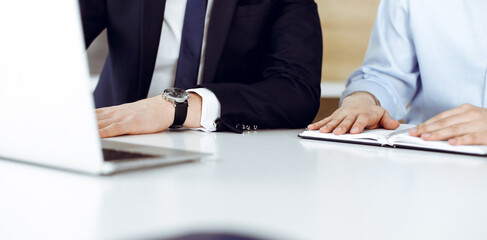 Unknown business people using laptop computer at the desk in modern office. Businessman or male entrepreneur is working with his colleague. Teamwork and partnership concept