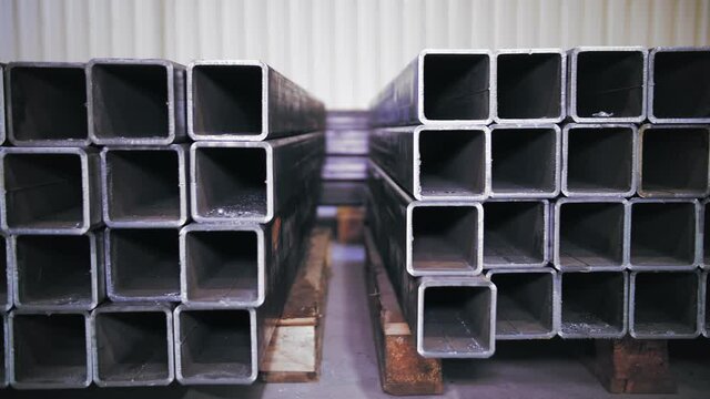 stacks of square metal pipes, steel tubes in warehouse. Laser cutting of metal pipes.