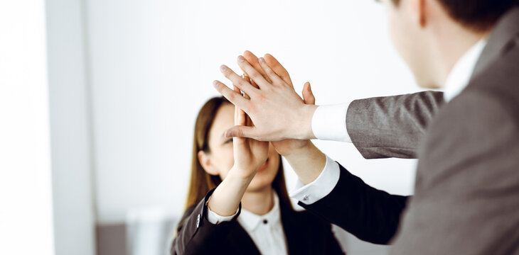 Unknown business people group joining hands in modern office. Businessmen and women making circle with their hands as a team, close-up