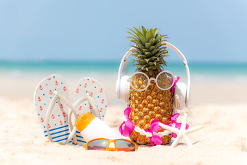 Fototapeta na wymiar Summer in the party. Hipster Pineapple Fashion in sunglass and listen music with sunblock and sandal on the sand beach beautiful blue sky background. 