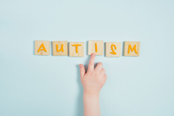 childish hand and lettering autism on wooden square blue background