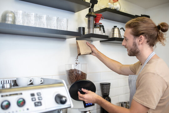 Man Pouring Coffee Beans Into Coffee Grinder