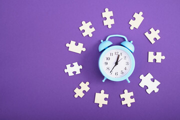 alarm clock and puzzles on purple background, puzzle pieces and clock, time concept