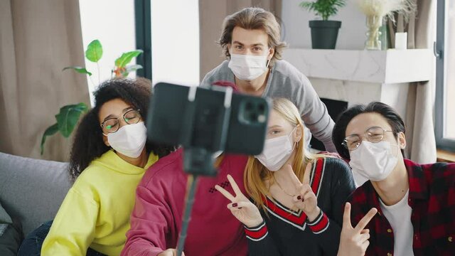 Clouse up group of mixed race friends making selfie celebrating at home with medical protection mask. Happy people indoor are having party at the coronavirus new normality time