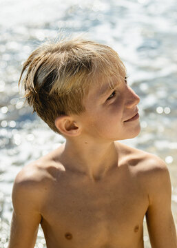 Candid portrait of young kid shirtless at the beach.