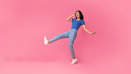 Fototapeta na wymiar Cheerful young asian lady jumping at studio