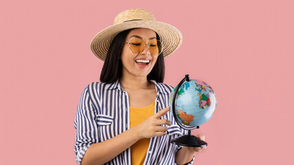 Asian woman holding geographic globe at studio