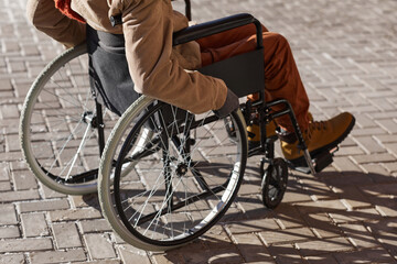 Cropped shot of unrecognizable African American man in wheelchair moving in urban city lit by...